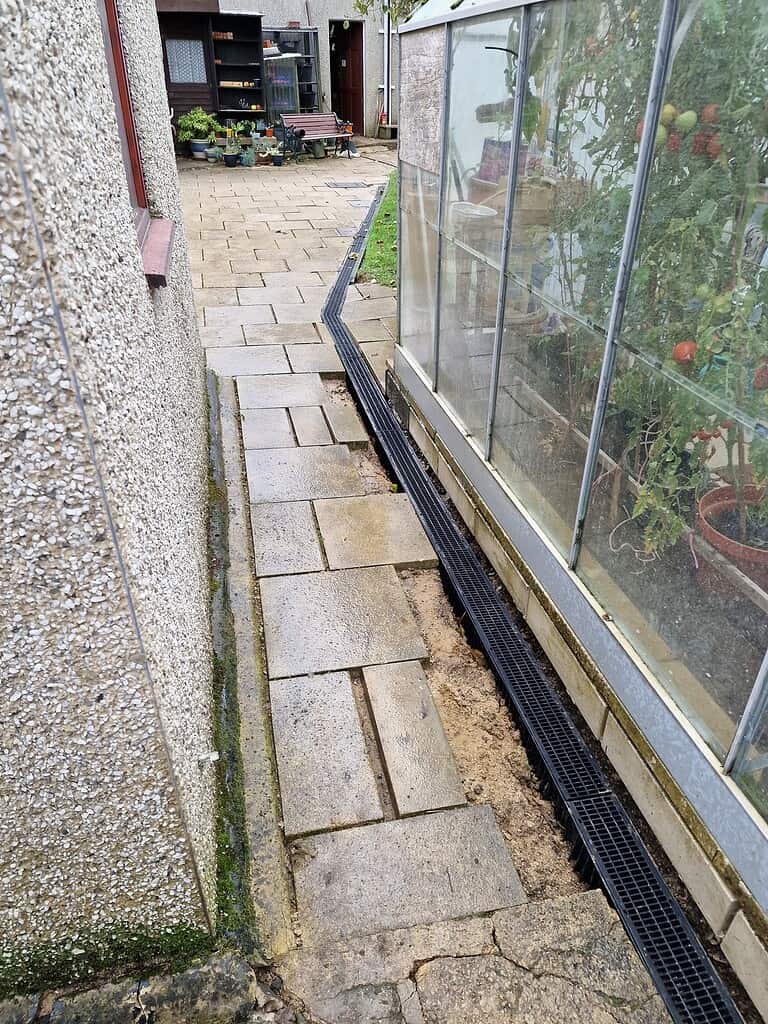 Heavy-duty site drainage channel installation along garden path in gardening and landscaping project.