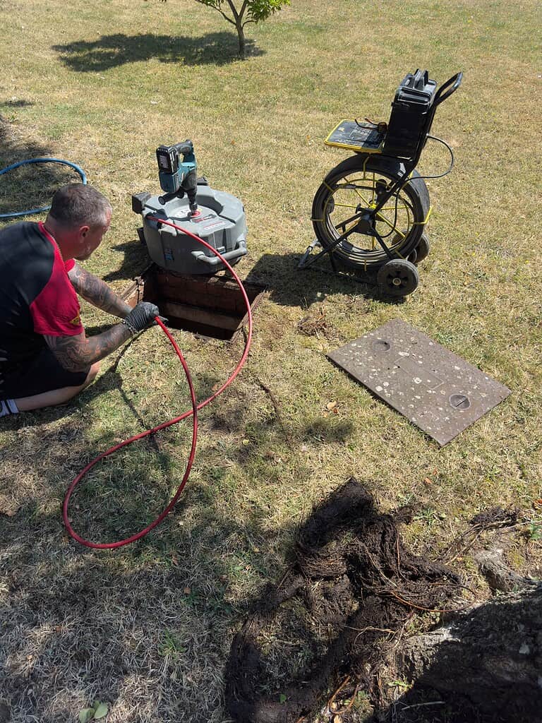 Technician inspecting drain with CCTV camera and root cutting equipment.