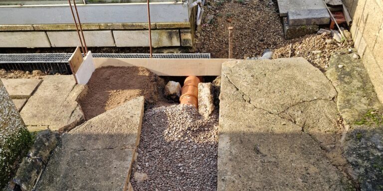 Blocked drainage pipe installation for garden drainage solutions.