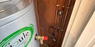 Close-up of hot water cylinder and copper pipework in a domestic heating system.
